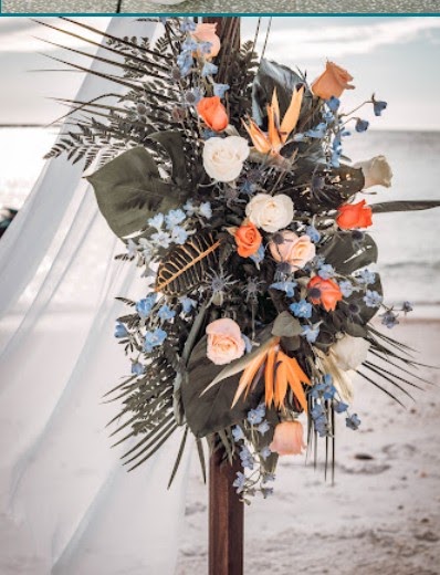 Tropical arbor arrangement with orange roses, birds of paradise and palm leaves on the beach