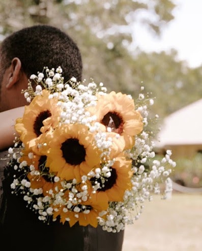 Sunflower and baby's breath bouquet held over a groom's shoulder