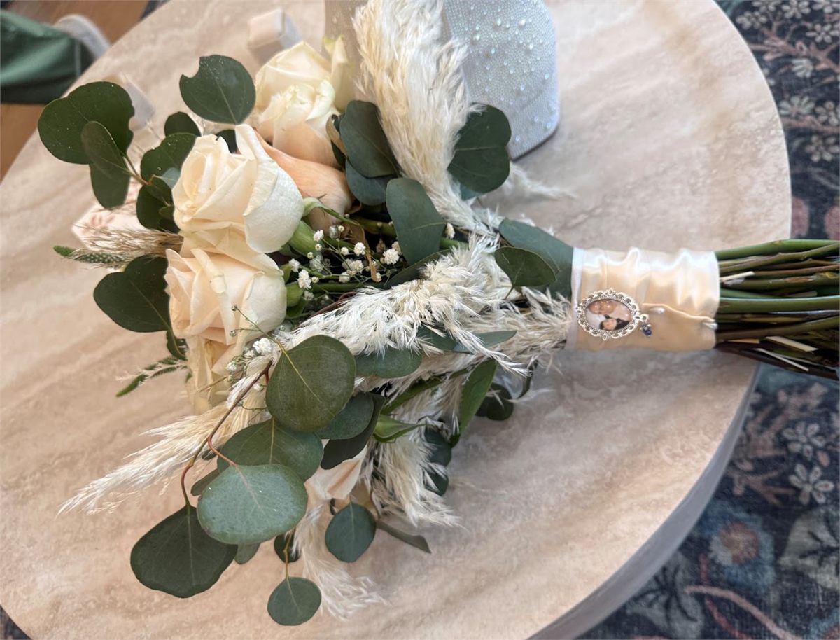 Bouquet of cream roses with eucalyptus and dried pampas grass on a wooden table