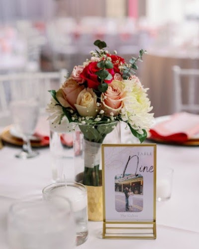 Low centerpiece of red, peach and cream flowers beside a framed table number