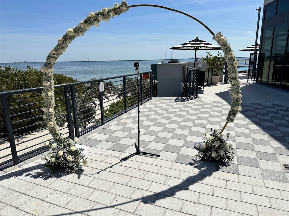 Circular floral arch with white flowers on an outdoor waterfront patio