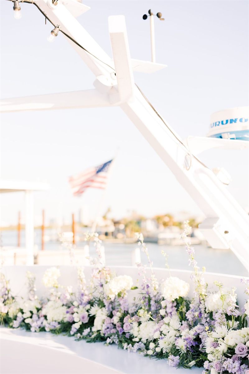 Garland of white and lavender flowers along a railing, with an American flag in the background