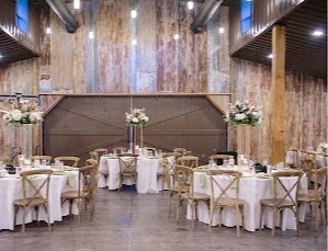 Barn reception hall with tall floral centerpieces on round tables