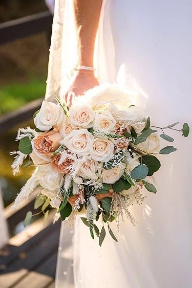 Bride holding a blush and cream bouquet of roses and eucalyptus