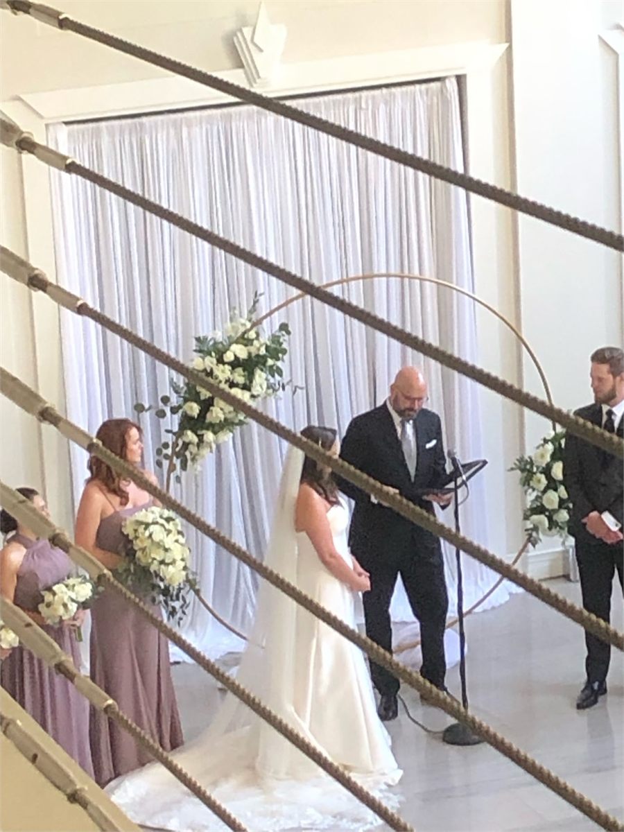 Ceremony taking place in front of a circular floral arch with white draping
