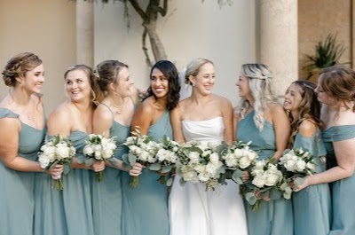Bride with six bridesmaids in sea green dresses holding white bouquets