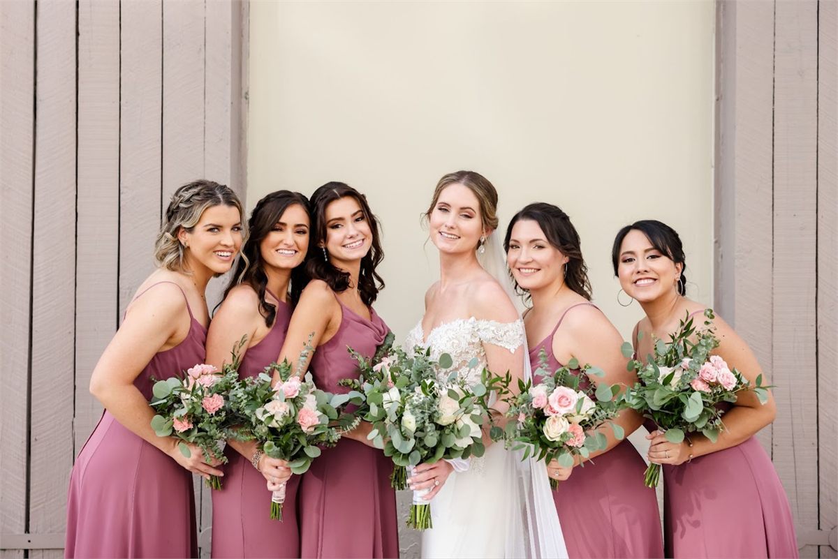 Bride and five bridesmaids in mauve dresses holding blush and cream bouquets